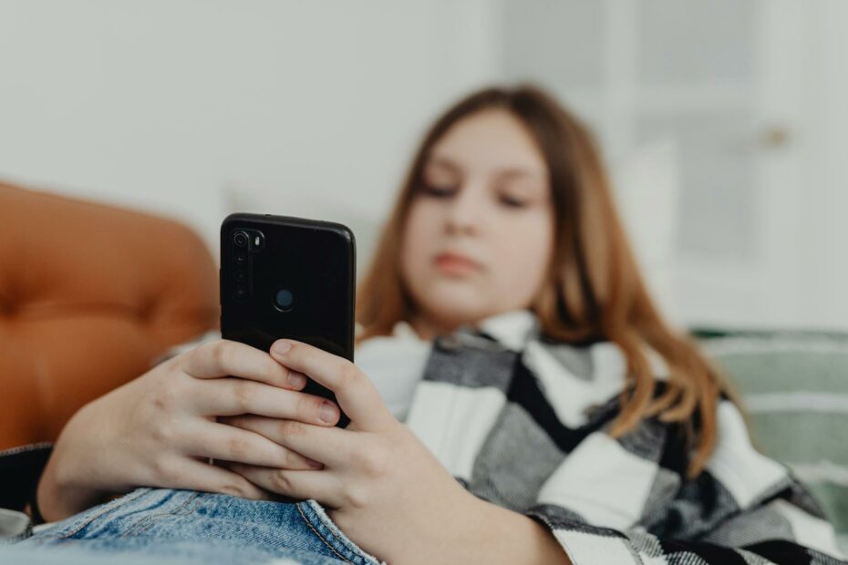 girl lying on sofa and using smartphone